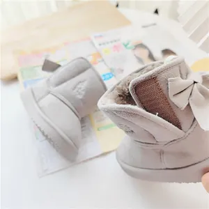Close-up of children's grey snow boots with faux fur lining and bow detail