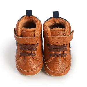 Detailaufnahme brauner Leder-Babystiefel mit warmem orangefarbenem Futter und Klettverschluss.