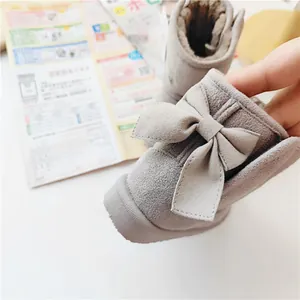Close-up of grey children's snow boots with a large bow and soft warm faux fur lining.
