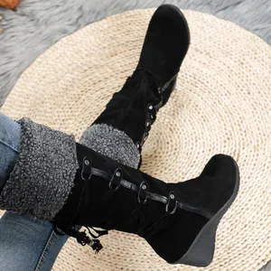 Detailed view of black suede-like high boots featuring grey faux fur trim and wedge heel