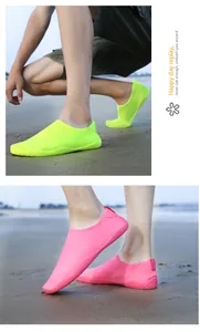Primo piano di scarpe da scoglio neon su una spiaggia sabbiosa per snorkeling e nuoto