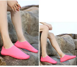 Scarpe da acqua rosa leggere per snorkeling e nuoto mostrate su terreno roccioso all'aperto