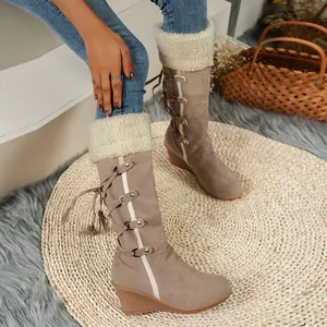 Detailed view of women's taupe suede wedge boots with faux fur lining and tassels