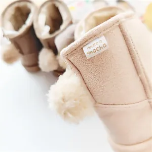 Close-up detail of children's warm winter snow boots with soft fleece and pom-poms