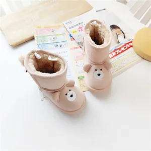 Close-up detail of cute pink bear-shaped baby snow boots with warm thick fleece lining