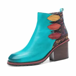 Detalle de botines de cuero turquesa hechos a mano con bordado étnico y detalles de hojas.