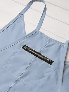 Detailaufnahme eines hellblauen Overalls mit V-Ausschnitt und Reißverschlusstasche.