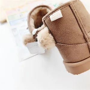 Close-up of brown children's snow boot showing fuzzy fur lining and poms