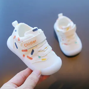 Detailed view of white toddler walking shoes with colorful sprinkle pattern and velcro.