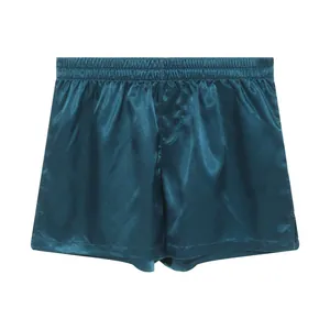 Close-up detail of men's teal satin loungewear shorts with elastic waistband.