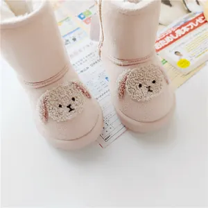 Close-up of pink children's snow boots with plush cartoon dog design and warm lining