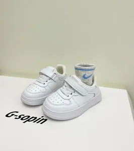 Close-up detail of white toddler sneakers with soft soles and adjustable velcro straps