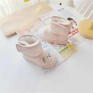 Detail of pink baby snow boots with cute cartoon dog and warm fleece lining