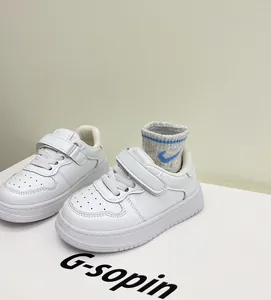 Close-up detail of white toddler sneakers featuring adjustable velcro strap closures.