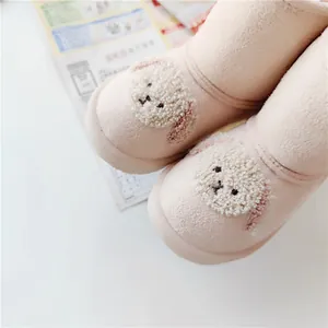 Close-up detail of pink children's snow boots with cute cartoon dog applique