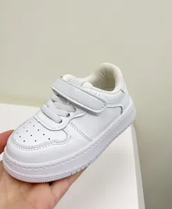 Close-up detail of white toddler sneaker with velcro strap and perforated toe box