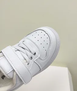Detail view of white leather toddler sneakers with velcro strap and breathable toe box