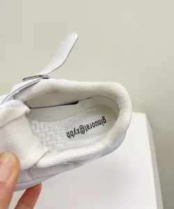 Close-up of white baby sneaker interior showing the padded collar and mesh insole detail