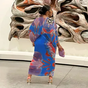 Vista trasera de un vibrante vestido largo plisado con mangas murciélago en una galería.