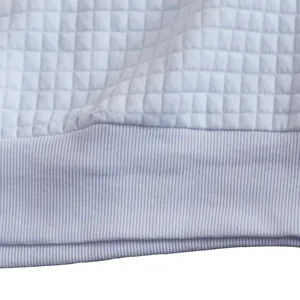 Dettaglio ravvicinato del tessuto a maglia trapuntato bianco e bordo a costine da uomo