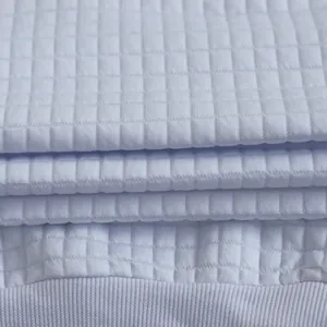 Dettaglio ravvicinato della maglia bianca con una trama a piccoli quadretti a rilievo