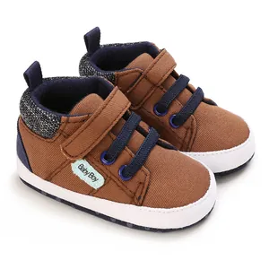 Vista detallada de zapatos de lona marrón para bebés con suela blanda y etiqueta Baby Boy.