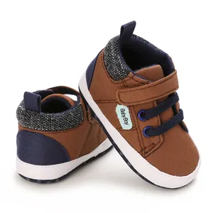 Vista detallada de zapatos de lona marrón para bebés con suela blanda y etiqueta Baby Boy.