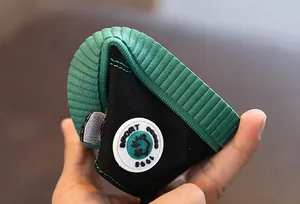 Detail der flexiblen grünen Gummisohle am schwarzen Kinder-Canvas-Schuh zeigt Weichheit