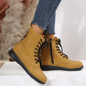Vue détaillée des bottines à lacets jaune moutarde sur une surface en marbre blanc