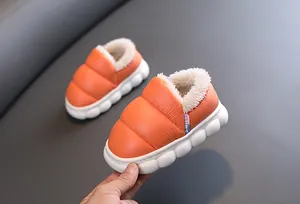 Close-up of orange waterproof children's winter shoes with soft white fleece lining.