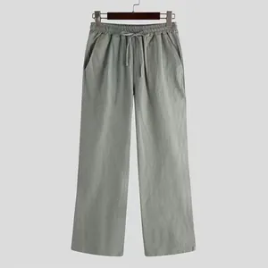 Loose-fitting men's casual trousers in a sage green solid color hanging on a rack
