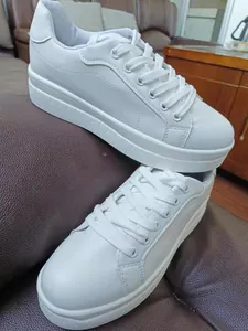 Vista dettagliata di sneaker bianche con plateau, design stringato e suola molto spessa
