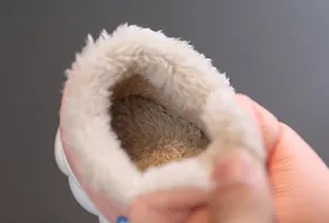 Close-up detail of thick warm white plush lining inside pink winter snow boots for kids