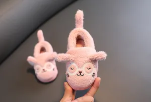 Nahaufnahme von rosa Plüsch-Kinderschuhen mit süßem gesticktem Katzengesicht-Detail