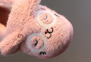 Detaillierte Makroansicht der niedlichen rosa Katzenstickerei auf warmen Winterhausschuhen.