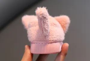 Nahaufnahme der flauschigen rosa Kinderhausschuhe mit Katzenschwanz und Gummisohle