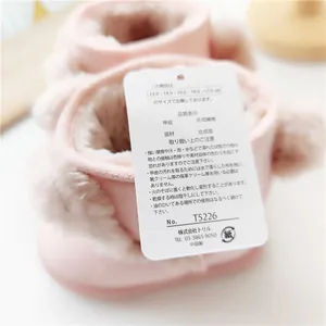 Primo piano dell'etichetta della taglia e del materiale degli stivali da neve rosa per bambini.