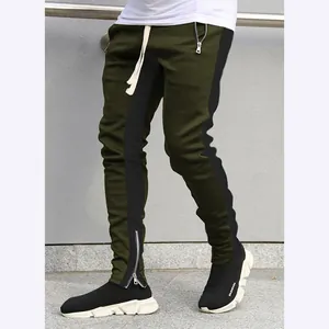 Detailed view of olive green joggers with black side stripes and ankle zippers.