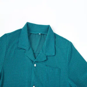 Detailed macro view of a teal men's waffle knit shirt featuring a camp collar and white buttons