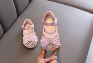 Detailaufnahme von rosafarbenen Mädchenschuhen mit funkelnden Strassschleifen und Pailletten