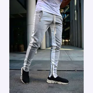 Detail view of gray slim fit men's joggers with white side stripes and ankle zipper accents