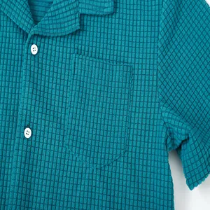 Macro view of teal waffle knit fabric and chest pocket on a men's button-up shirt