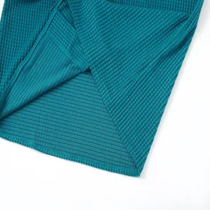 Close-up of teal waffle knit fabric texture and neat hem stitching of a men's shirt.