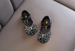 Detailansicht schwarzer Mädchenschuhe mit glitzernden Strasssteinen und Schleife