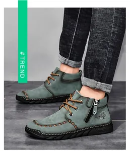 Detailed view of sage green men's mid-top work boots with side zipper and decorative stitching