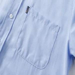 Close-up detail view of a blue men's Oxford shirt pocket showing the fine fabric texture