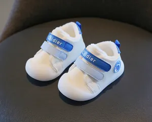 White fleece-lined baby walking shoes with blue velcro straps and soft sole detail
