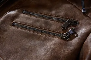 Vue détaillée de deux poches zippées en métal sur une veste en similicuir marron