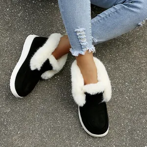 Detailweergave van zwarte suède winterschoenen met witte rand van imitatiebont en platte zool.