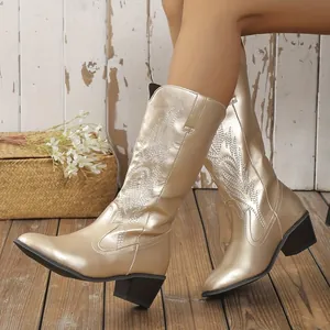 Gros plan de bottes mi-mollet dorées avec de magnifiques broderies florales vintage